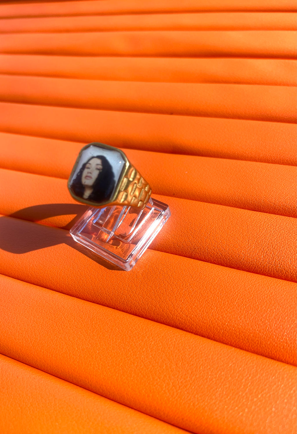 18K gold-plated Cleo Sol-inspired Lav Vintage promise ring with square face, photographed on an orange background.
