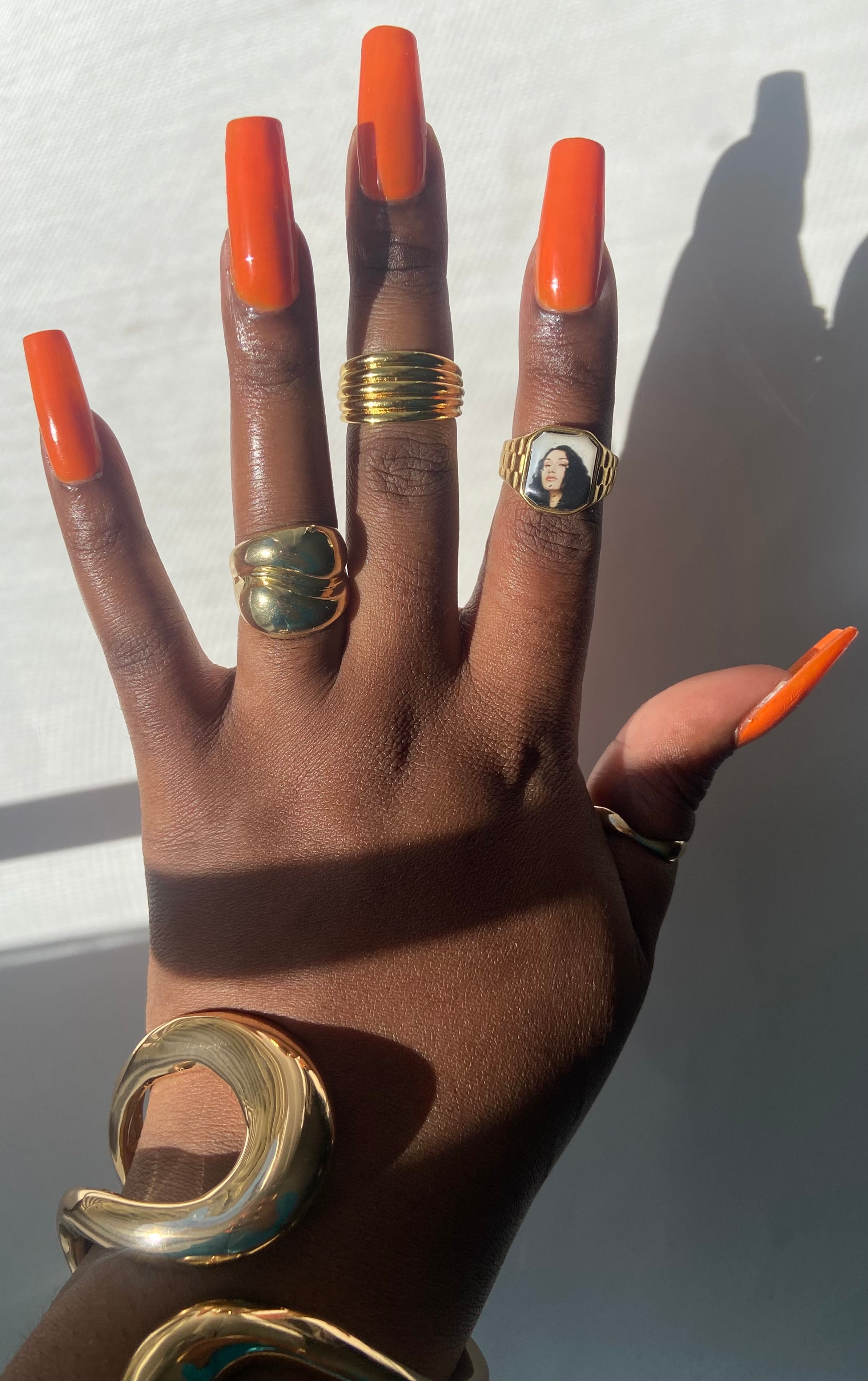 Hand wearing stacked gold rings including a Cleo Sol-inspired Lav Vintage promise ring, styled in natural sunlight.
