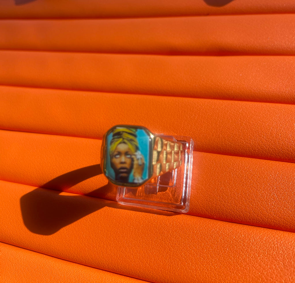 18K gold-plated Erykah Badu-inspired Lav Vintage promise ring with square face, photographed on an orange background.

