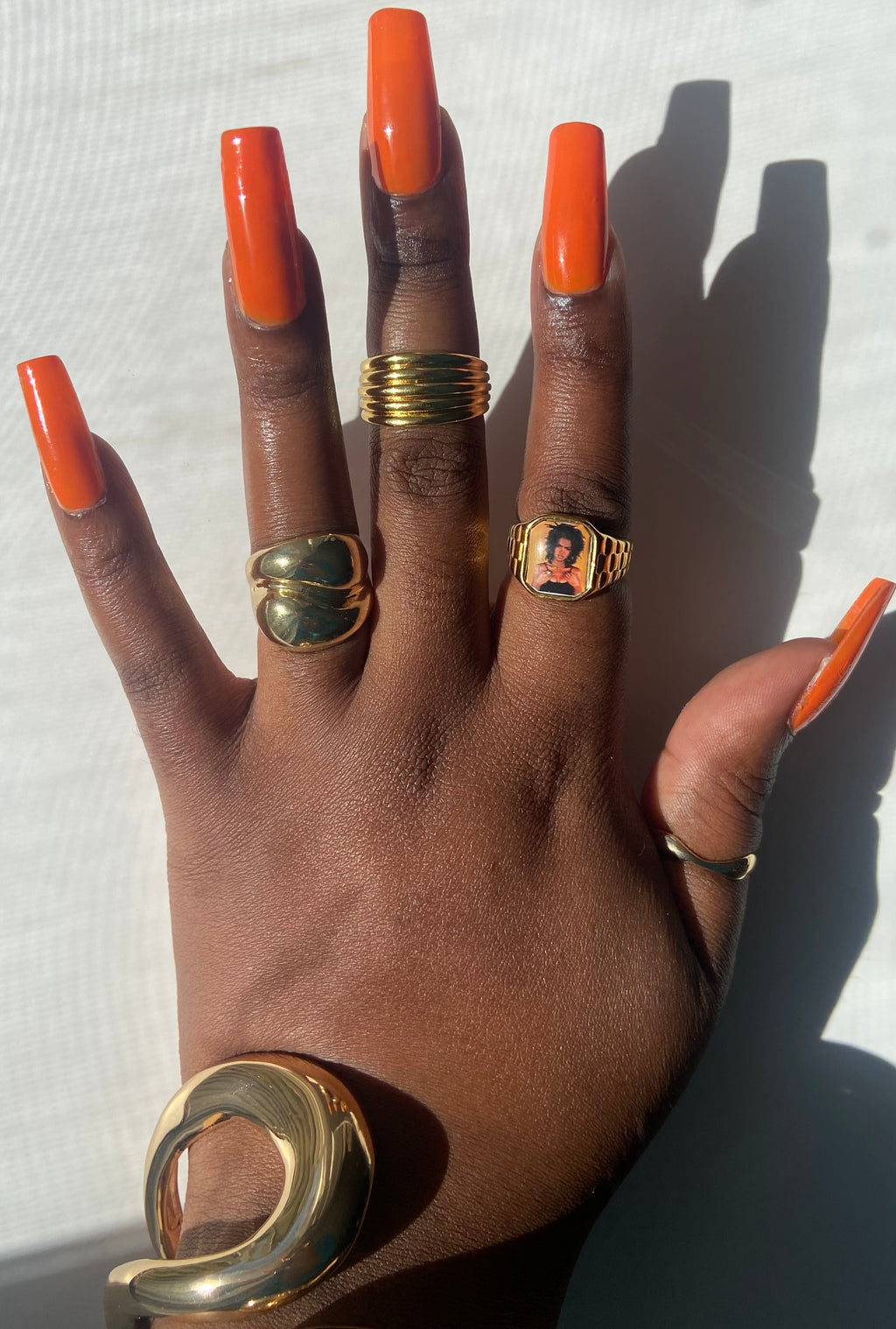 Hand wearing stacked gold rings including a Lauryn Hill-inspired Lav Vintage promise ring, styled in natural sunlight.