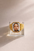 Square 18K gold-plated promise ring featuring a Sade-inspired portrait, styled on a soft neutral surface.