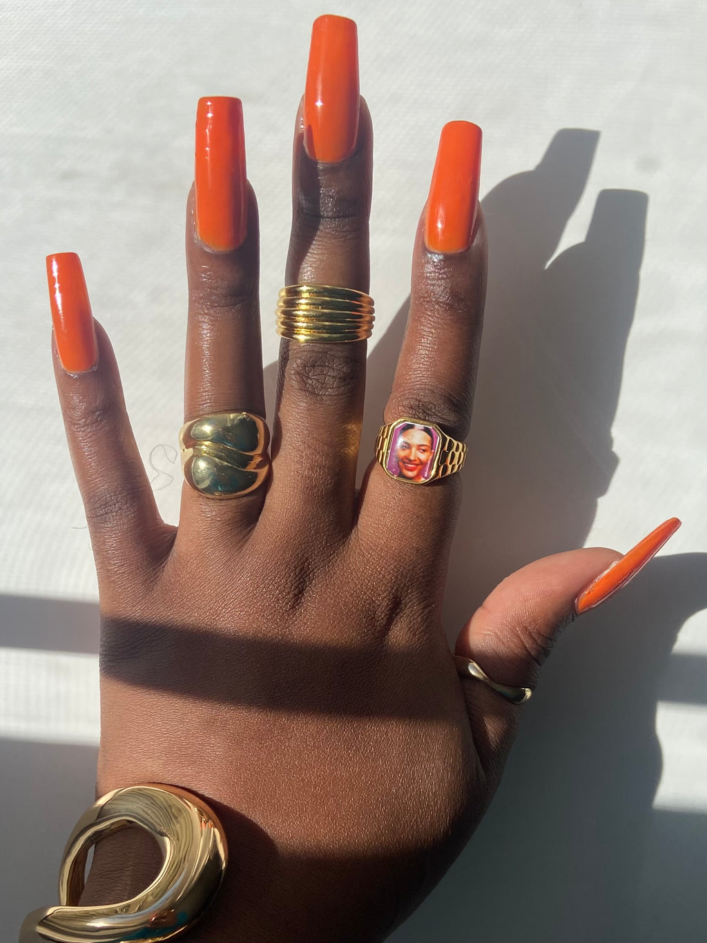 Hand wearing stacked gold rings including an Olivia Dean-inspired Lav Vintage promise ring, styled in natural sunlight.