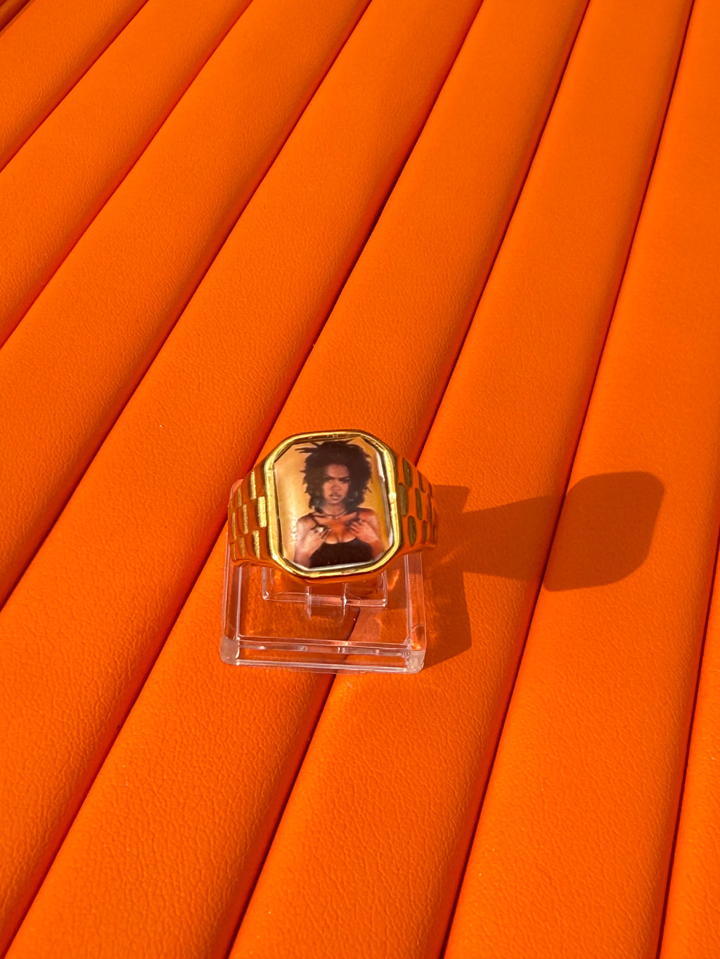 18K gold-plated Lauryn Hill-inspired Lav Vintage promise ring with square face, photographed on an orange background.

