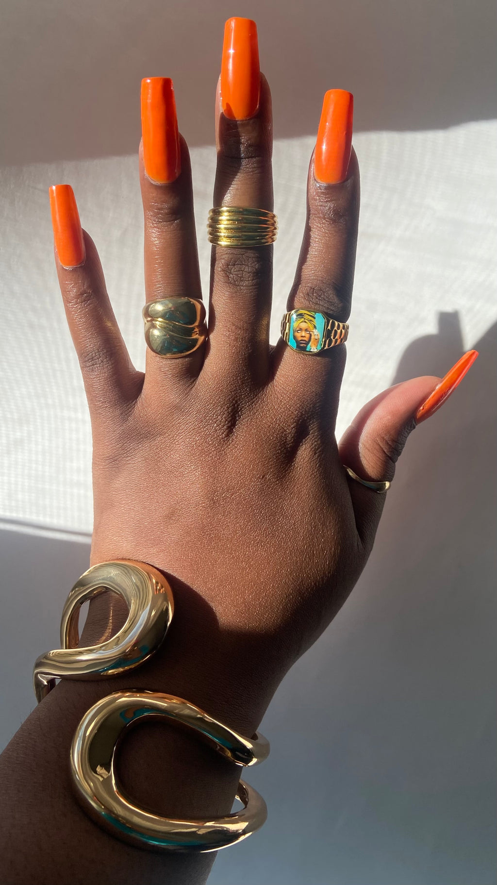 Hand wearing stacked gold rings including an Erykah Badu-inspired Lav Vintage promise ring, styled in natural sunlight.