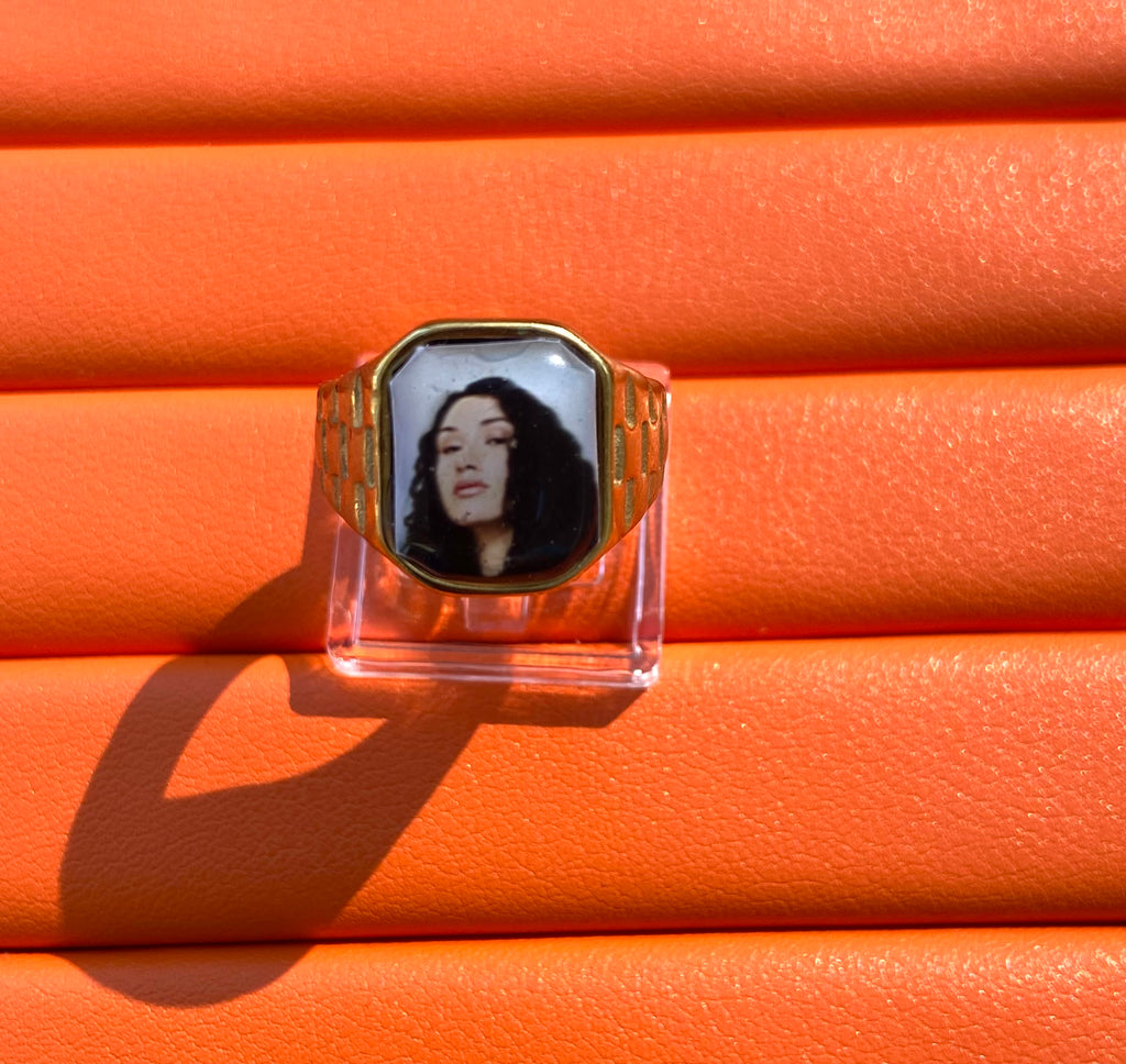18K gold-plated Cleo Sol-inspired Lav Vintage promise ring with square face, photographed on an orange background.
